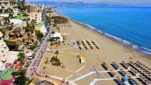 Ein Strand mit einem Haufen geparkter Autos und dem Ozean in der Unterkunft El Cortijuelo. Magnificent triplex terraced house with rooftop of 18m2, overlooking the sea. Parking in Torremolinos