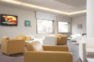 a waiting room with couches and chairs and a tv at Best Western Hotel Continental in Udine