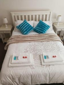 a white bed with blue pillows and towels on it at 11 Portobelo in Mossel Bay