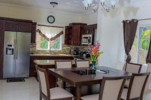 kuchnia ze stołem z krzesłami i lodówką w obiekcie Tropical Luxury Dreams w mieście Ocho Rios