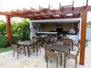 een patio met tafels en stoelen onder een pergola bij Apto em Maitinga/Bertioga in Bertioga