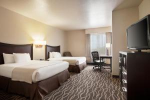 a hotel room with two beds and a flat screen tv at Baymont by Wyndham Clute Lake Jackson in Clute