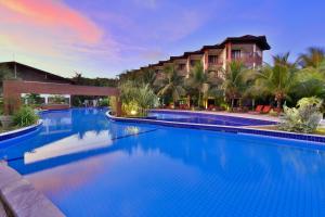 una piscina resort con un hotel en el fondo en Aruanã Pousada en Jacumã
