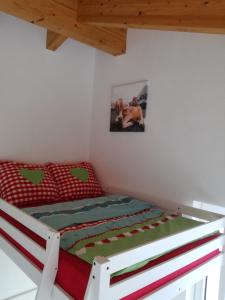 Schlafzimmer mit einem Bett mit einer roten und grünen Bettdecke in der Unterkunft Ferienhaus Hubertus für 8 Personen in Pill