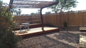 a wooden deck with a chair and a pergola at צימרגולה in ‘En Yahav