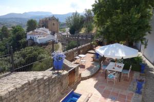 a patio with a table and a white umbrella at La Escondida Ronda, B&B in Ronda