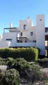 un edificio blanco con arbustos delante de él en Casa Patrick, en Murcia