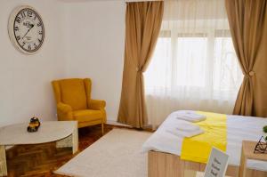 a bedroom with a bed and a clock and a chair at Joy City Stay Prefectura 1 in Timişoara