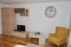 a living room with a clock on the wall and a chair at Central apartment with BIG room, WiFi, TV, Washer in Timişoara