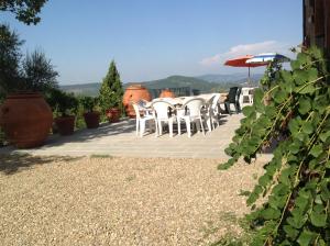 grupa białych krzeseł i parasol na patio w obiekcie Agriturismo Prato Barone w mieście Rufina
