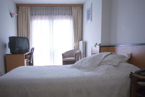 une chambre d'hôtel avec un lit et une télévision dans l'établissement Hotel Des Zouaves, à Coxyde