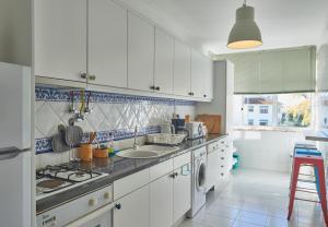 a kitchen with white cabinets and a sink and a dishwasher at Cascais Handsome Apartment in Cascais +19 photos