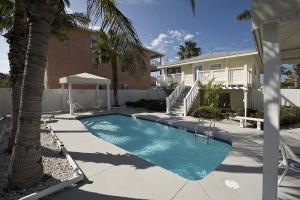 a pool with a pool table and chairs in front of a house at Bungalow Beach Resort in Bradenton Beach