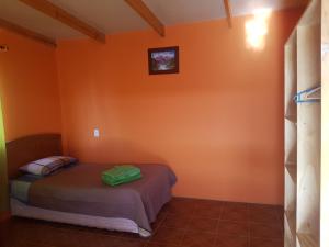 Un dormitorio con una pared de color naranja y una cama. en Hostal Casa Colque, en San Pedro de Atacama
