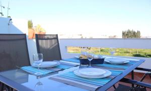 una mesa azul con platos y copas de vino. en Central apartment-terrace and pool, en Cabanas de Tavira