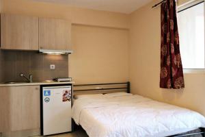 a small bedroom with a bed and a refrigerator at Mango in Paralia Katerinis