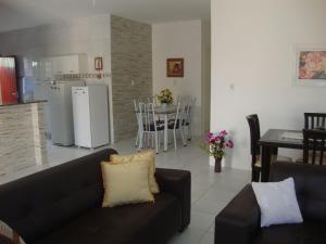 a living room with a black couch and a kitchen at Casa Praia de Tamandaré PE in Tamandaré