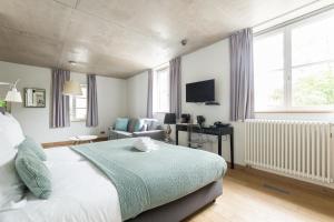 a bedroom with a bed and a couch and a television at La Pipistrelle Hotel in Luxembourg