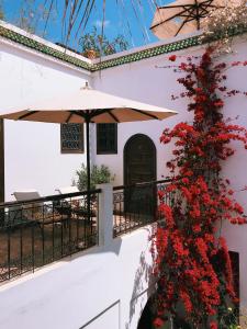 - un balcon avec des fleurs rouges et un parasol dans l'établissement Riad Clémentine, à Marrakech