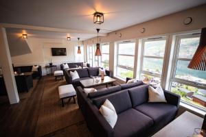 una sala de estar con sofás, mesas y ventanas en Grande Fjord Hotel, en Geiranger