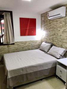 ein Schlafzimmer mit einem Bett und einem roten Gemälde an der Wand in der Unterkunft Chale Mamelucos em Frente A Praia de Ipitanga Salvador Bahia in Salvador