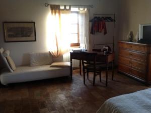 a bedroom with a couch and a desk and a window at PoggioBa in Sovana