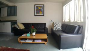 a living room with two black leather couches and a coffee table at Austria Motel in Paihia