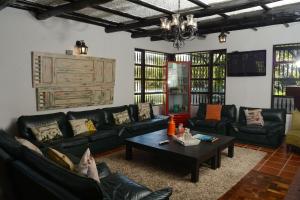 Sala de estar con sofás negros y mesa de centro en Casa Finca Corales Llano Grande 1, en Rionegro