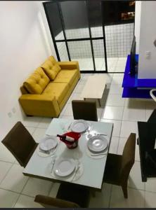 una mesa y sillas en una habitación con sofá amarillo en Cobertura duplex com piscina a beira-mar de Guaxuma en Maceió