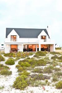 a house on the beach with a field of grass at Hemel op Aarde Villa in Dwarskersbos