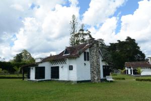 an old white house with a roof on a field at Casa Finca Corales Llano Grande 2 in Rionegro