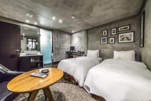 a bedroom with two beds and a table and a sink at Hotel Cello in Seoul