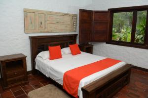 a bedroom with a bed with red pillows and a window at Casa Finca El Embrujo in Rionegro