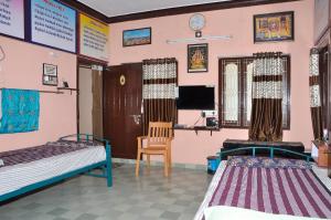 a room with two beds and a tv at Homestay Senthil Akam in Chidambaram