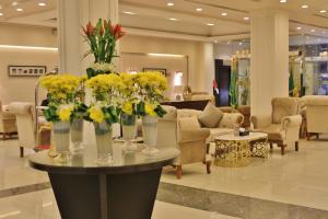 un vestíbulo con flores amarillas en jarrones sobre una mesa en Carawan Al Fahad Hotel, en Riad