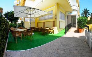 a patio with tables and chairs and an umbrella at Residence Riviera in Alba Adriatica