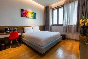 a bedroom with a bed and a desk and a red chair at Icity Villa Riverfront Danang in Danang