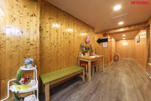 a room with a wooden wall with a bench and tables at Seoul Station R Guesthouse in Seoul