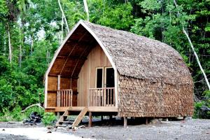 małą chatę z dachem krytym strzechą w obiekcie Tanjung Kalemo Resort w mieście Batudaka