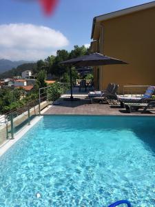 a large blue swimming pool with an umbrella and chairs at Merck Villa Gerês in Rio Caldo