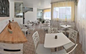 アルバ・アドリアティカにあるResidence Rivieraの白いテーブルと白い椅子が備わるレストラン
