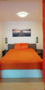 1 dormitorio con 1 cama con colcha de color naranja en Appartmenthaus Kern, en Aigen im Mühlkreis
