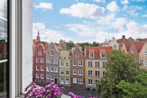 a view of a city from a window with purple flowers at Flatbook - In the Heart of Old Town Apartments Sw Ducha in Gdańsk