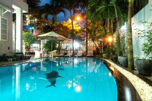 een zwembad 's nachts met een dolfijn in het water bij The Moon Villa Hoi An in Hội An