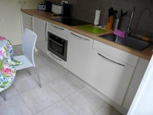 エクスレバンにあるLe Beau Site - Studioの白いキャビネット、シンク、椅子付きのキッチン