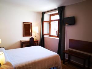 um quarto de hotel com uma cama e uma janela em Hotel Santa Bàrbara De La Vall D'ordino em Ordino