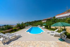 a swimming pool with lounge chairs and an umbrella at Guest House Villa Bellevue 1 in Cavtat