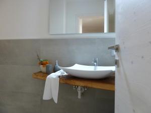 een badkamer met een witte wastafel en een spiegel bij Casa Lassù in Carano