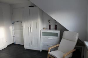 Habitación con silla blanca y cómoda en Fewo Seifert, en Schortens