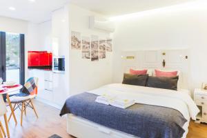 ポルトにあるAPOSENTUS - Your Home at Pinheiro's Studioの白いベッドルーム(ベッド1台付)、キッチンが備わります。